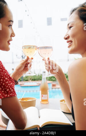 Recht glücklich Asiatische weibliche Freunde sitzen, Schwimmbad und guten Wein und Gespräch Stockfoto