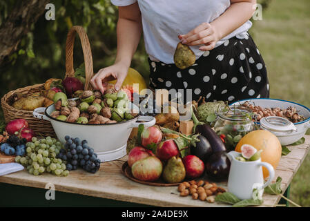 Frau um einen Tisch mit Obst und Gemüse, die eine Birne, Serbien Stockfoto