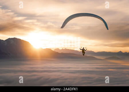 Mann Paragliding über den Wolken bei Sonnenuntergang, Salzburg, Österreich Stockfoto