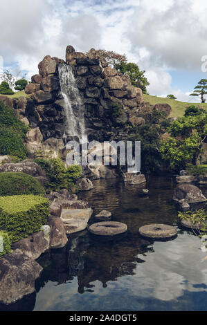 Jeju Island, South Korea, September 05, 2019: wunderschöne Landschaft mit Wasserfall und Teich innerhalb von temperamentvollen Garten auf bewölkten Tag Stockfoto