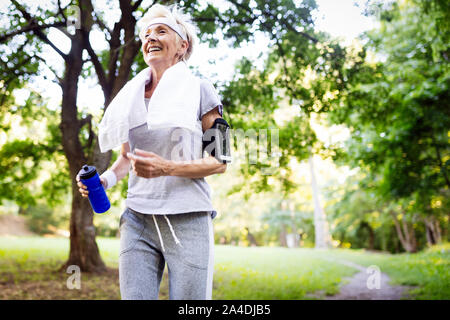 Portrait von lächelnden Sportliche ältere Frau mit Handtuch im Freien Stockfoto