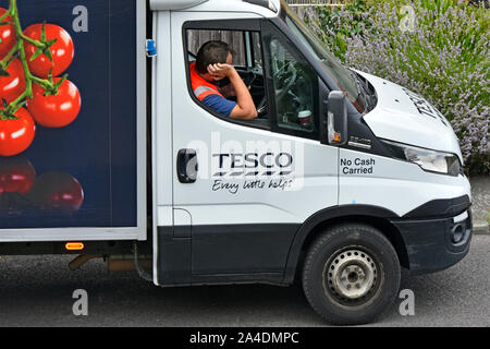 Straße. Szene Nahaufnahme des Tesco Supermarkt Home food supply chain Anlieferung Treiber Mann kommt früh & wartet in Van für seinen Kunden Essex England Großbritannien Stockfoto