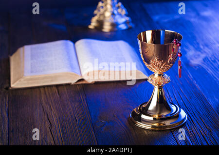 Christentum Symbole Komposition. Das Kreuz, Bibel, Rosenkranz und goldenen Kelch auf Holz- Hintergrund. Stockfoto