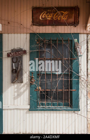 Das Zeichen sagt Willkommen, aber die Reben erzählen eine andere Geschichte an eine alte Tankstelle in der Nähe von Pipe Creek in Bandera County, Texas Stockfoto