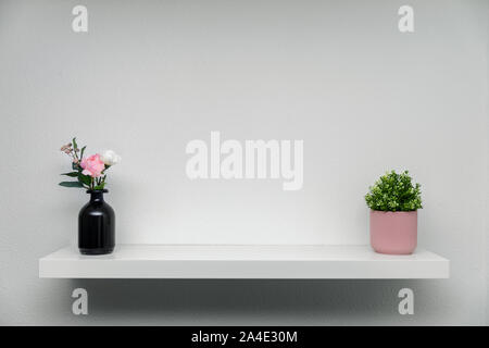 Holzregal auf weiße Wand mit grünen Pflanzen Blumenvase Stockfoto