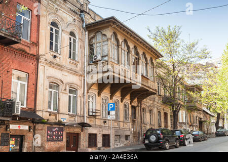 Tiflis, Georgien - 28. April 2019: Tiflis Blick auf die Straße mit Autos in der Nähe von Old Wohn häuser mit traditionellen geschnitzten Holzbalkonen geparkt Stockfoto