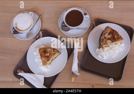 Panettone Schichten mit Sahne, Tasse Kaffee und Tasse Schokolade auf Holztisch. Ansicht von oben. Frühstück für zwei. Stockfoto