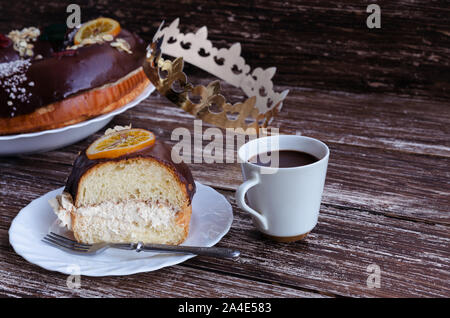 Roscon de Reyes Slice und Tasse heiße Schokolade auf Holz- Hintergrund. Traditionelle spanische Weihnachtskuchen mit Krone Erscheinung oder Dia de Rey zu cerebrate Stockfoto