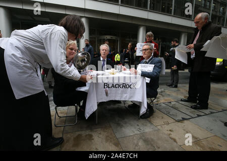 Demonstranten essen Geld" als eine Form der Demonstration vor dem BlackRock Hauptsitz in Throgmorton Avenue in London, während ein Aussterben Rebellion (XR) Klimawandel protestieren. Stockfoto