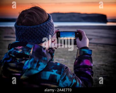 Anonyme unkenntlich Traveler schießen Sonnenuntergang am Meer Stockfoto