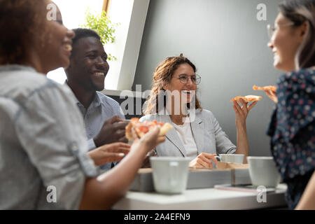 Multirassische Gesellschaft Mitglieder zu Mittag essen Pizza in der Pause Stockfoto