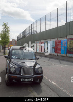 Black Cab am Frieden Linie entlang Cupar Weg in Belfast. Stockfoto