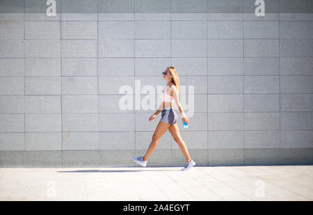 Junge Frau mit fit Körper gegen grauen Hintergrund. Weibliche Model in Sportswear Outdoor Aktivitäten. Stockfoto