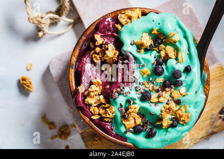 Gesund vegan Frühstück. Spirulina und Beeren smoothie Schüssel mit Müsli, grauen Hintergrund. Stockfoto