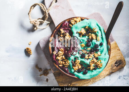 Gesund vegan Frühstück. Spirulina und Beeren smoothie Schüssel mit Müsli, grauen Hintergrund. Stockfoto