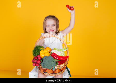 Schöne Mädchen hält einen Korb mit Gemüse reif Stockfoto