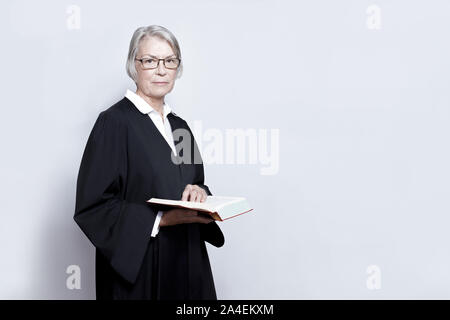 Weibliche Rechtsanwalt Konzept: reife Frau in einem schwarzen Kleid mit einem legislativen Text Book, kopieren. Stockfoto