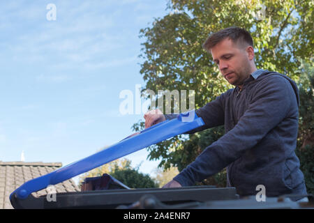 Kaukasische Mann warf ein Papier in einem blauen plastik Müll bin. Stockfoto