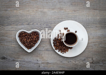 Espresso Kaffee auf einem Holztisch mit Kaffeebohnen in einem Herzen shaoed Schüssel Stockfoto