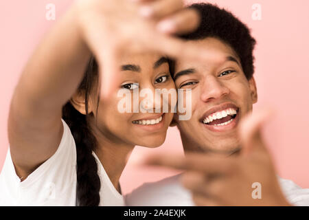 Freudige afro Paar framing Gesichter mit Händen Stockfoto