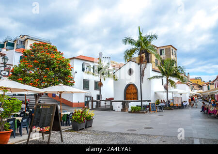 Funchal, Madeira, Portugal - September 10, 2019: Straße in Madeiras Hauptstadt mit typischen Restaurants und Cafés. Die Menschen trinken und essen auf der Terrasse im Freien. Koloniale Architektur. Das historische Zentrum. Stockfoto