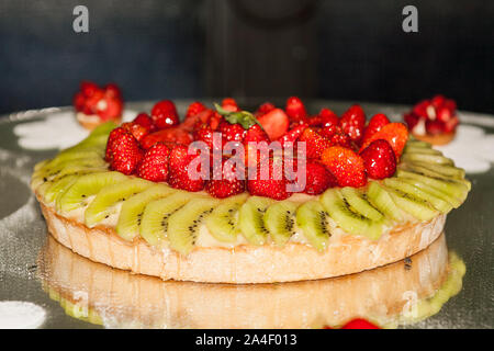 Erdbeere und Kiwi Kuchen, Obst Kuchen mit Vanillecreme, weiße Blume Zucker Dekoration. Stockfoto