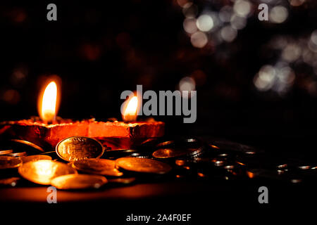 Horizontale Ebene mit zwei Terrakotta Lampen und Münzen - Diwali Wohlstand Konzept im Hinduismus Stockfoto