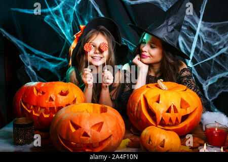 Mutter und ihrer Tochter in Hexe Kostüme Halloween Feiern mit Halloween Süßigkeiten und süße über Spider web Stockfoto