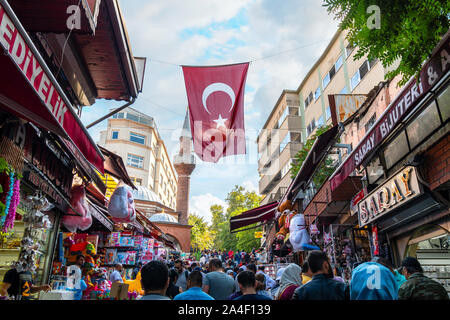 Lokale Türken genießen Sie die expansiven Markt im Freien Basar, wie Sie unter einem fliegenden Türkische Flagge in Istanbul, Türkei. Stockfoto