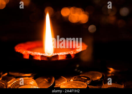 Einzigartige Perspektive auf ein Lehm verwendete Lampe Häuser in Diwali zu verzieren, auf einem Haufen von Münzen, die für den Wohlstand Konzept plaziert Stockfoto