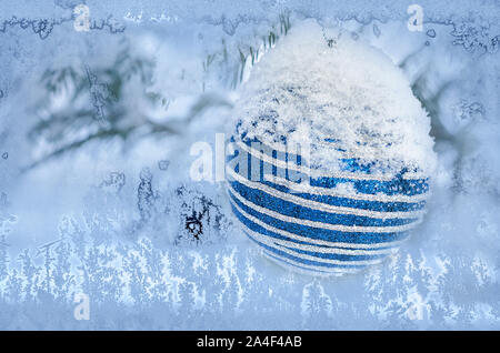 Der Weihnachtsbaum Kugel kann durch die gefrorenen Fenster Glas gesehen werden. Stockfoto