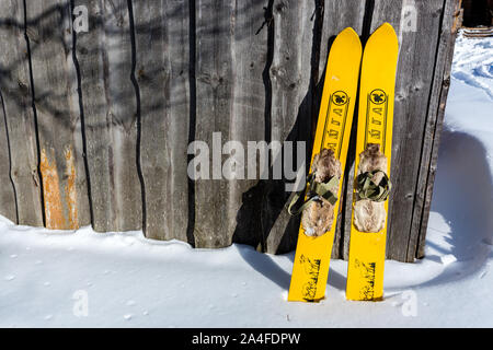Region Moskau, Russland - 24. Februar 2018: Paar Gelbe altmodischen hölzernen Skier in der Nähe von Altes Haus stehen auf weißen Schnee. Stockfoto