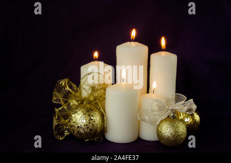 Brennende weiße Kerzen und goldenen Christbaumkugel mit Band Dekoration auf schwarzem Hintergrund Stockfoto