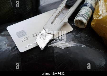 Löffel voller Heroin und Papier Messer liegt auf Droge Packs und Kreditkarte mit Dollars. Konzept des Drogenhandels und Umgang in den Usa te Stockfoto