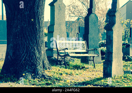 Bank unter Grabsteine auf dem Friedhof Stockfoto