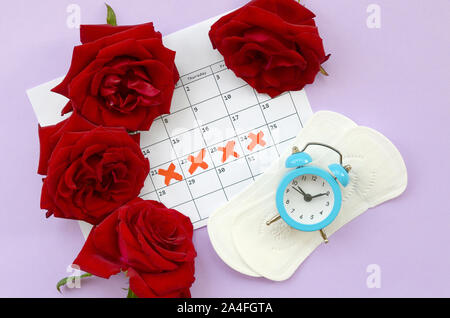 Pads auf der Menstruation Menstruation Periode Kalender Wecker mit blauen und roten Rosen. Aspekte der Frauen Wellness in Monatszeitschriften. Frau kritischen Tagen Stockfoto
