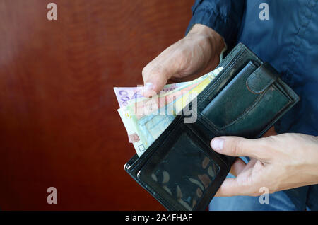 Nahaufnahme der männlichen Händen öffnete die Brieftasche oder Geldbörse mit ukrainischen Geld Währung Griwna. Gehalt in der Ukraine. Große Menge Geld Stockfoto