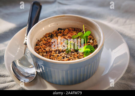 Gebackene oat-heidelbeere mit Minze in einer weißen und blauen Platte bröckeln auf einem urigen Bettwäsche Tischdecke. Speichern Sie die Raum, Ansicht von oben. Das Konzept der gesunden ordnungsgemäße Stockfoto