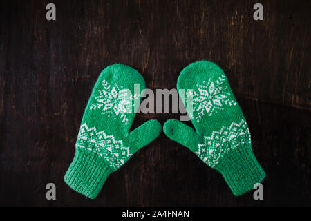 Ein paar Blau-grün Gestrickte Handschuhe auf einem dunklen Blau-grün-braun Holz- Stockfoto