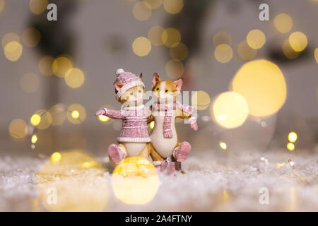 Dekorative Figuren aus einem Thema Weihnachten. Figurine von niedlichen umarmen Katzen in einen gestrickten Pullover, Schal und Hut bekleidet. Weihnachtsdekoration. Festi Stockfoto