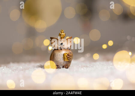 Dekorative figurine toy Eule mit einer goldenen Krone auf dem Kopf. Festliches Dekor, warme Bokeh leuchtet. Stockfoto