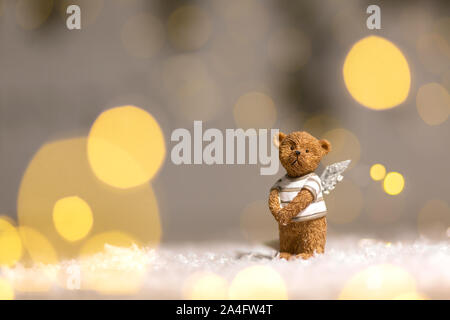 Dekorative Figuren aus einem Thema Weihnachten. Figurine eines süßen Bär mit Angel Wings. Festliches Dekor, warme Bokeh leuchtet. Stockfoto