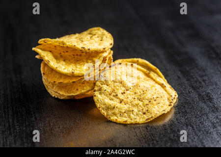Runde Nacho Chips. Gelbe Tortilla Chips auf Schwarz. Stockfoto