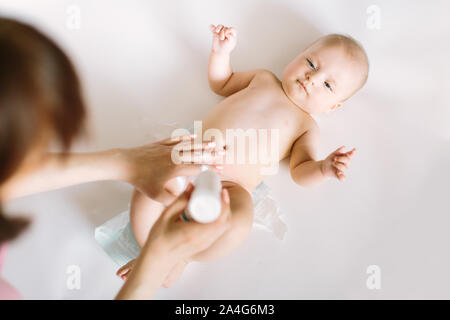 Mutter vorbereiten Baby Powder in Ihrer Hand und vier Monate altes Baby als Hintergrund. Stockfoto