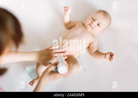 Mutter vorbereiten Baby Powder in Ihrer Hand und vier Monate altes Baby als Hintergrund. Stockfoto