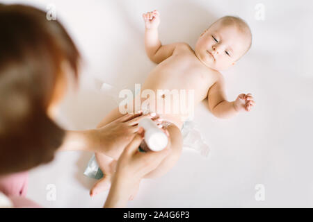 Mutter vorbereiten Baby Powder in Ihrer Hand und vier Monate altes Baby als Hintergrund. Stockfoto