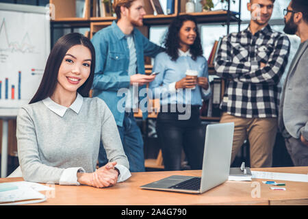 Startupers gemeinsam an Büro Frau am Tisch sitzt mit Laptop, Kamera freudige Stockfoto