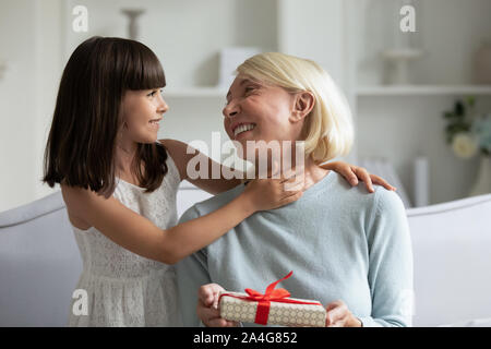 Kleine süße Enkelin vorbereitet Geburtstagsgeschenk für glückliche Oma. Stockfoto