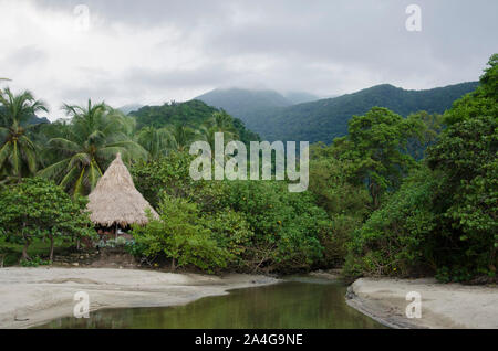 Im Vordergrund ein kleiner Wasserlauf, der von der Vegetation und der Handelsströme zwischen den Sand entsteht aufgrund einer intensiven Grün, eine kleine Kabine und die Stockfoto
