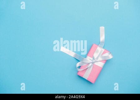 Urlaub blauen Hintergrund mit Geschenk, weiße Satinschleife, Ribbon. Valentinstag, der Tag der Frau, Muttertag, Geburtstag, Hochzeit, Weihnachten. Stockfoto